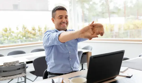 man sitting at a desk stretching his forearms