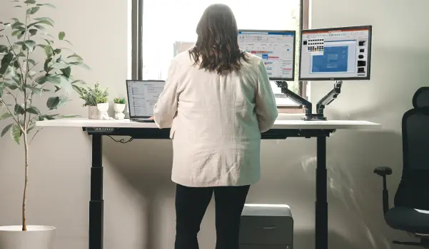 woman standing at her height-adjustable desk