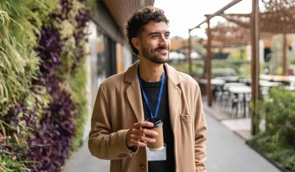 man walking outside holding a coffee cup for a quick break from the office